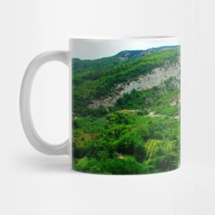 View in Castel Trosino at a ridge of rough mountain standing above human settlements Mug